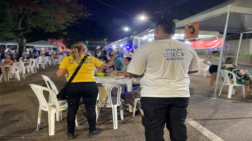 Executadas no período noturno, o Departamento Estadual de Trânsito – Detran Rondônia, por meio da Escola Pública de Trânsito – EPT realiza ações educativas com foco no público adulto, com orientações voltadas, especialmente, aos frequentadores de bares e festas. A ação “Motorista Camarada” é realizada por voluntários de educação, que, abordam pessoas orientando-as a não dirigirem após ingerir bebida alcoólica. Em Porto Velho, as ações aconteceram na sexta-feira (27), sábado (28) e domingo (29), e alcançou um público de 1.438 pessoas. Transmitindo a mensagem anual “No trânsito, escolha a vida”, os voluntários destacaram informações sobre: – A distração coloca você em risco: o fator humano é a causa principal dos sinistros. – Se for beber, nunca dirija: dirigir exige reflexos rápidos, que são prejudicados pelo álcool, mesmo em pequenas doses. – Motociclista, siga com atenção e cuidado: os motociclistas são os mais vulneráveis no trânsito. – Ajude sempre: trate os outros usuários com educação e respeito. O coordenador da ação “Motorista Camarada” da noite de sábado (28), Carlos Romeu Fernandes explicou que, o Código de Trânsito Brasileirto – CTB penaliza quem bebe e dirige, criminalmente ou administrativamente. Se o teste do etilômetro identificar nível até 0,33 miligramas de álcool por litro de ar alveolar expelido, a pessoa vai responder processo administrativo, conforme o artigo 165 do Código de Trânsito Brasileiro. Caso o etilômetro registre a partir de 0,34 miligrama de álcool por litro de ar alveolar expelido, caracteriza crime de trânsito, conforme previsto no artigo 306 do CTB; o condutor é preso em flagrante e conduzido à Central de Polícia. Para responder em liberdade, o condutor tem que pagar fiança estipulada pelo delegado que conduziu o flagrante. O diretor-geral do Detran/RO, Léo Moraes destacou a relevância de um trânsito mais seguro e consciente. “Beber e dirigir é uma atitude perigosa para todos, e o Departamento executa as ações educativas para orientar e sensibilizar as pessoas sobre seus deveres no trânsito”, salientou. Dados Subordinada à direção-geral, a Escola Pública de Trânsito – EPT, responsável por realizar campanhas, seminários, encontros, conferências, fóruns, cursos e palestras educativas, conjuntamente a outros órgãos do Sistema Nacional de Trânsito, objetiva à redução de mortes e lesões no trânsito. De janeiro a outubro, a EPT executou os projetos: “Trânsito Seguro”, com foco no público infanto-juvenil, “Condutores em Ação” e “Motorista Camarada”, direcionados ao público adulto, com abordagens de total de 84.446 condutores em todo estado de Rondônia. Fonte Texto: Jarlana Davy Fotos: Jarlana Davy Secom - Governo de Rondônia